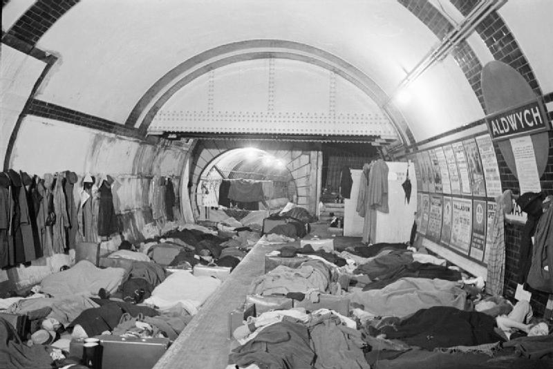 People lying and sitting along a tube platform and on the track bed, sheltering overnight