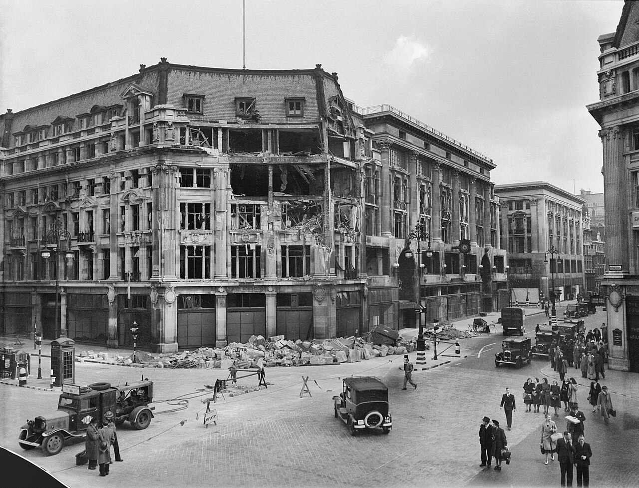 A large department store building with blown-out windows and bomb damage on a city corner