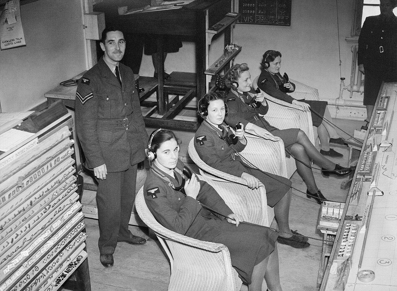 Two WAAF telephone operators wearing headsets at a desk in an operations room