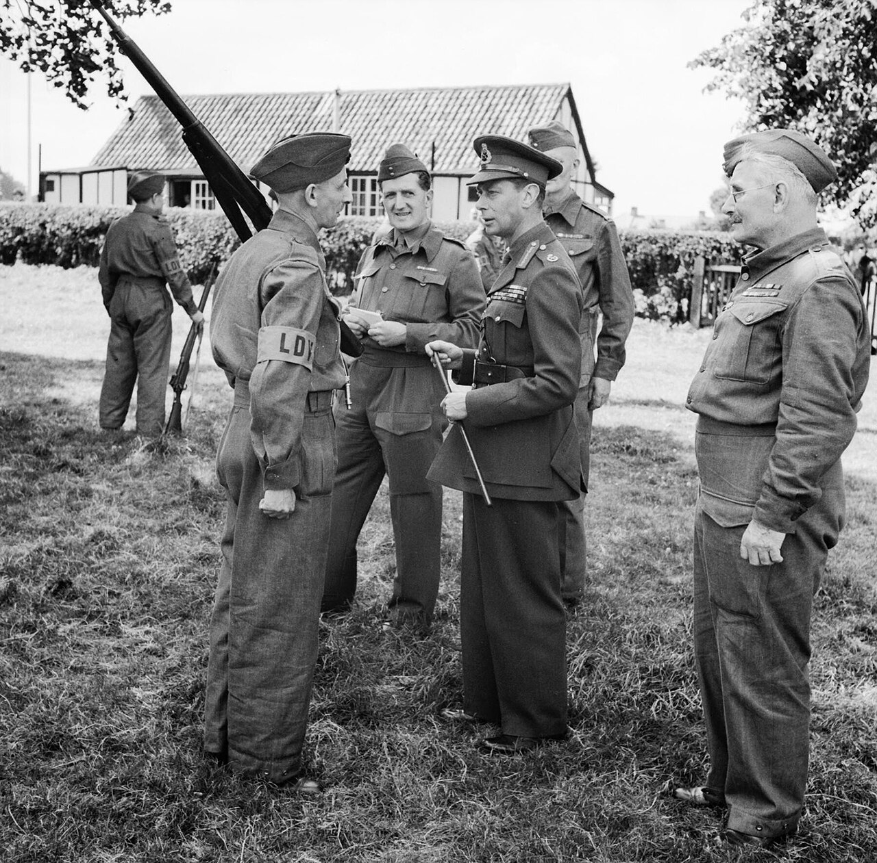 The King in uniform talking with Home Guard volunteers holding rifles