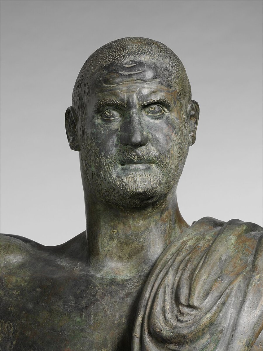 Detail of a Roman bronze statue of the emperor Trebonianus Gallus, showing the head and shoulders of a hard-faced, close-shaven man
