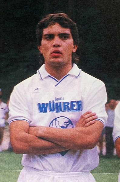 Branco as a young player in a white Brescia shirt, standing on a pitch with his arms folded