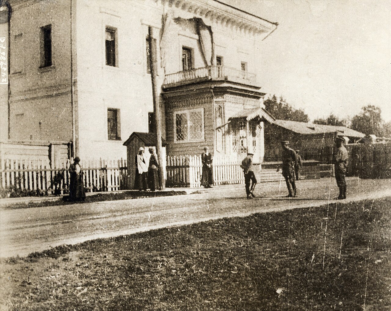 A large two-storey house on a wide provincial street with small figures outside
