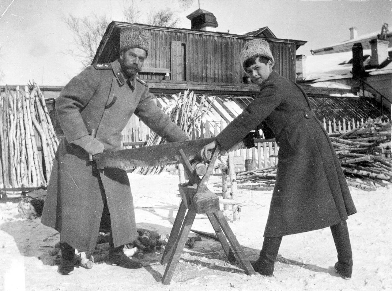 A man and a boy sawing a log together in deep snow