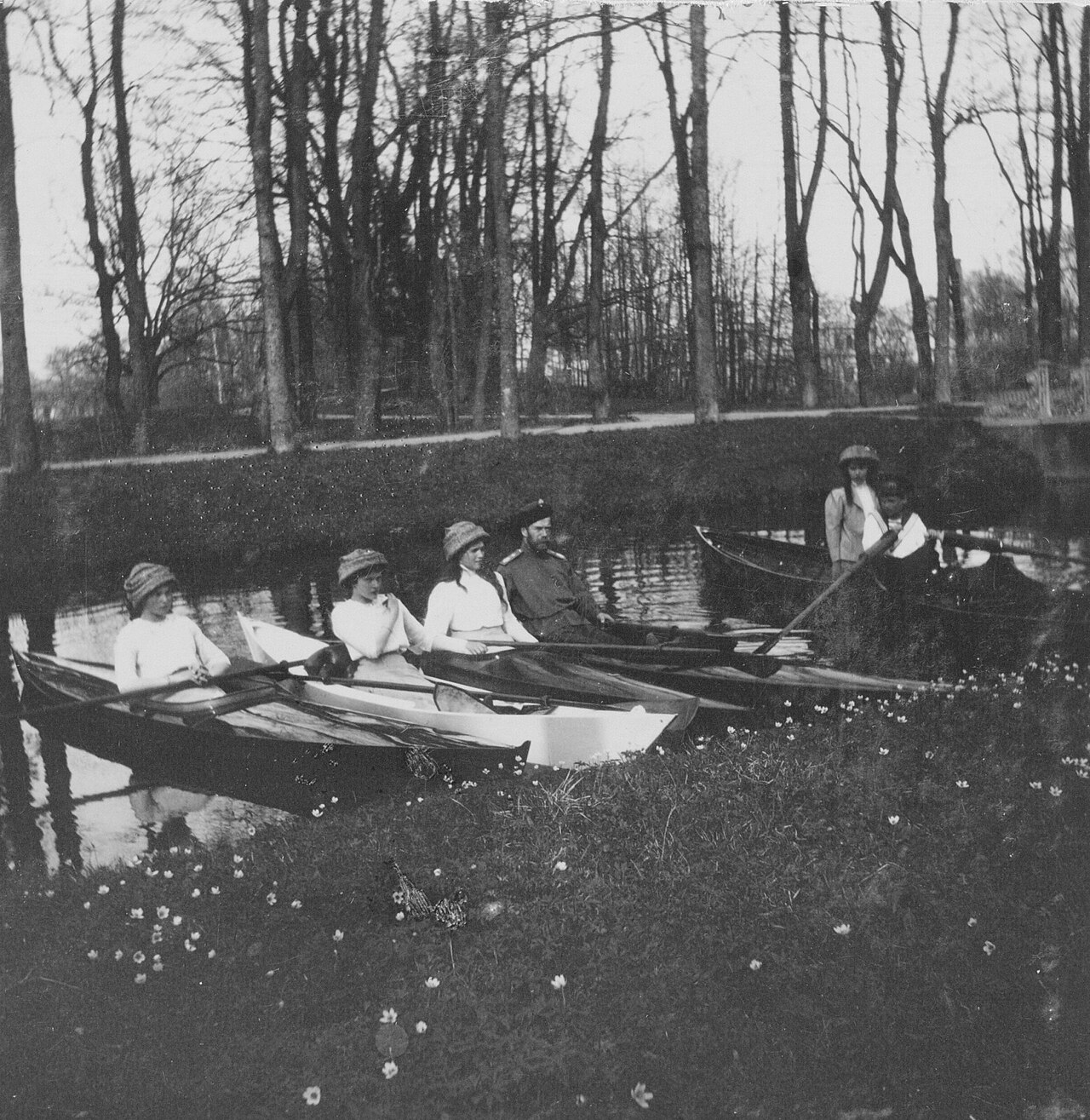 Two kayaks carrying several people on a wooded lake in a park