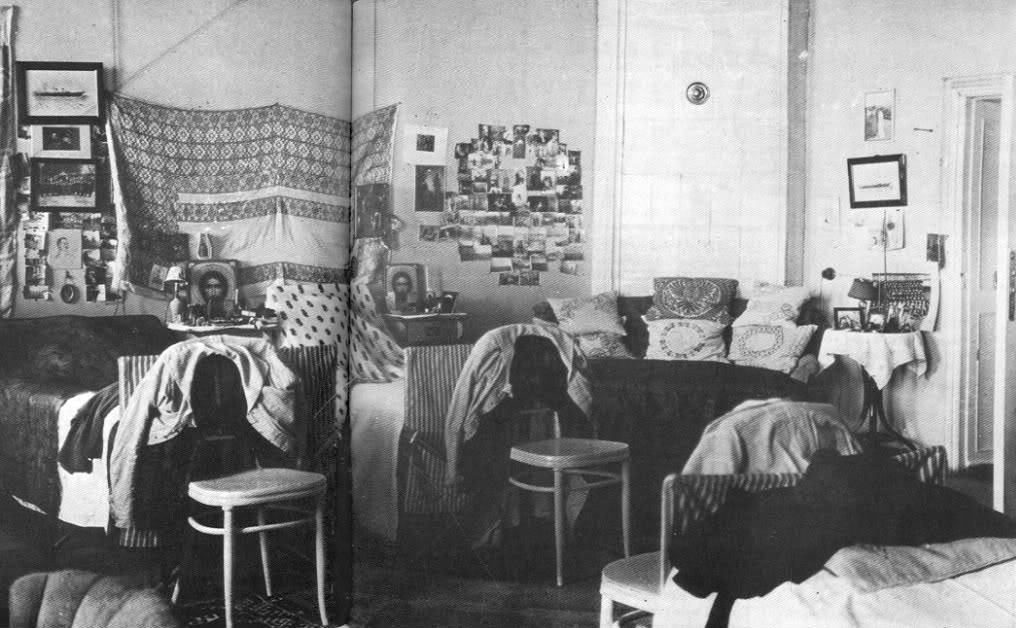 A plain bedroom with four camp beds, personal photographs and icons on the walls