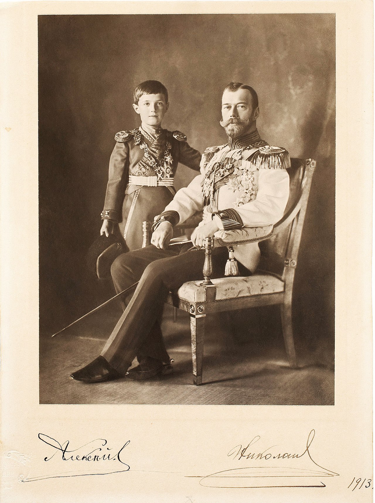 A seated studio portrait of a bearded man in uniform with a boy beside him, signatures below