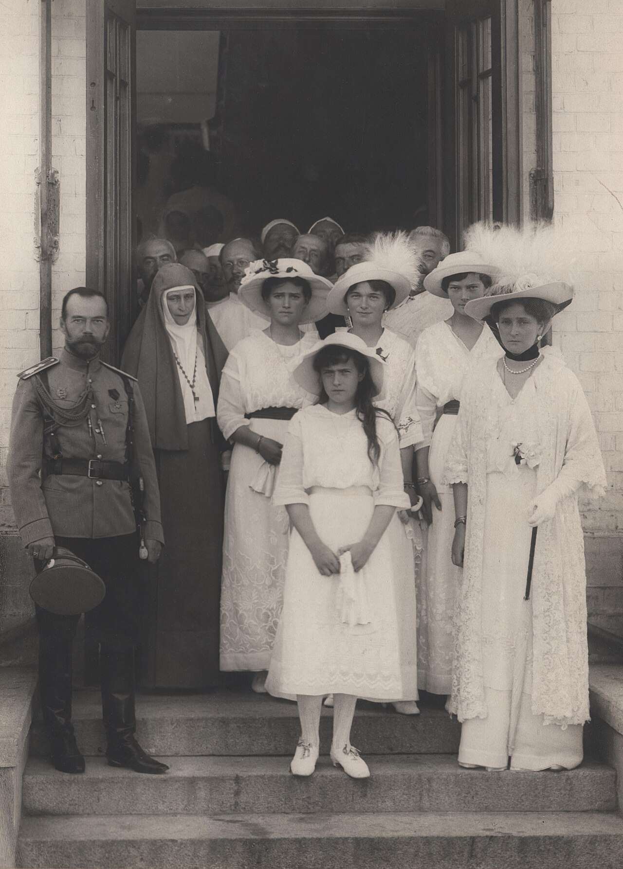 The imperial family with women in nursing dress on the steps of a hospital building