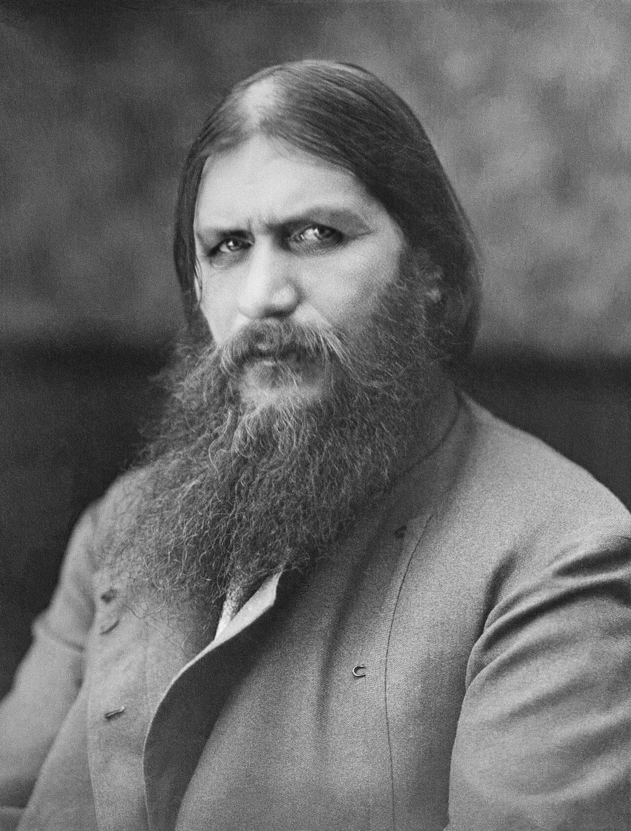 Portrait of a long-bearded man in a dark coat looking directly at the camera