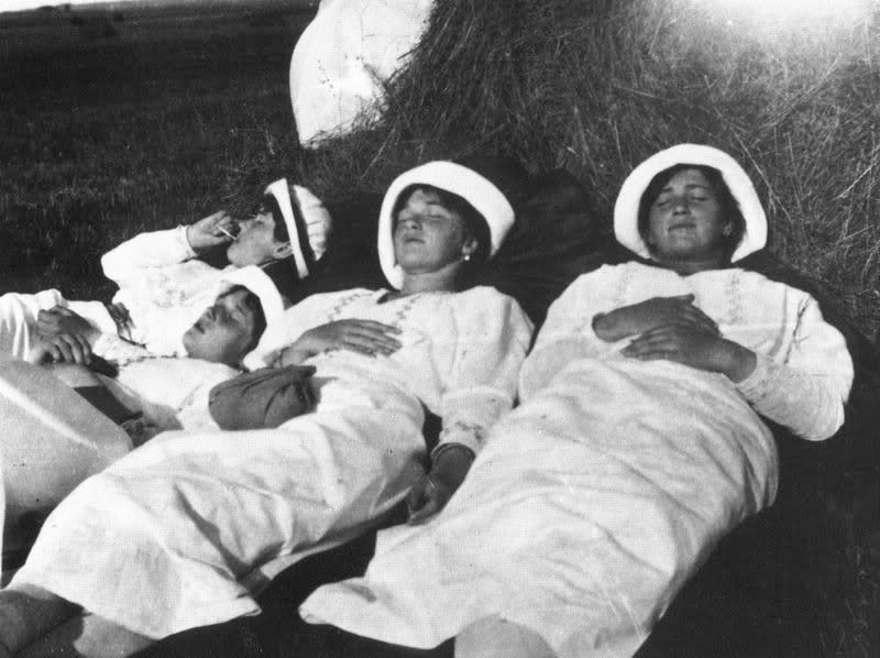 Four young women lying back in a haystack, laughing