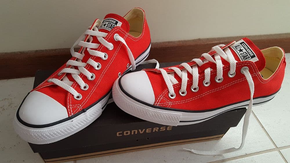 A pair of red low-top Converse Chuck Taylor All Star sneakers resting on their box