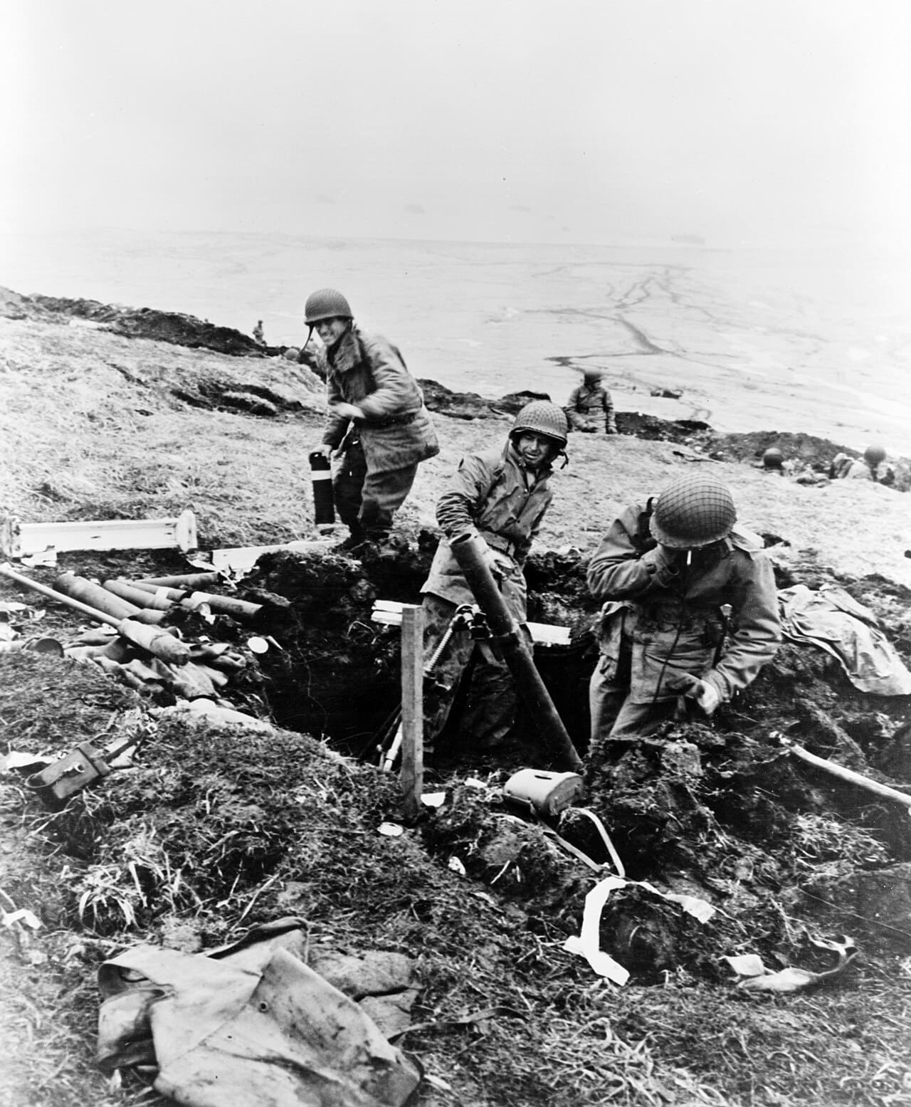 American soldiers firing a trench mortar from behind a bare ridge