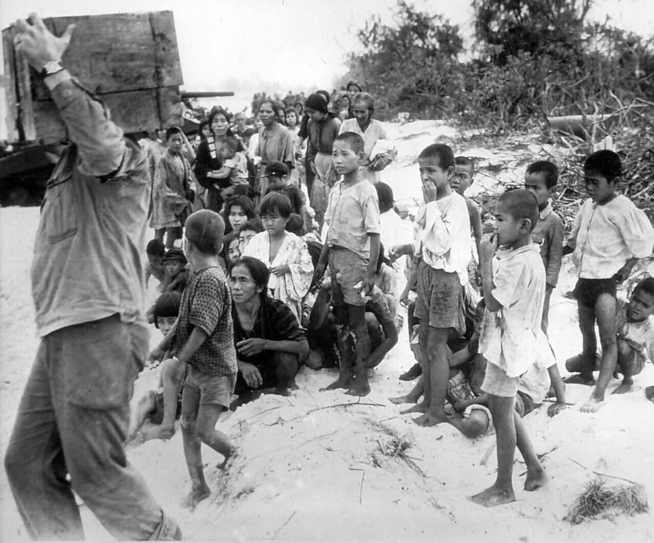 Civilian men, women and children gathered on a beach