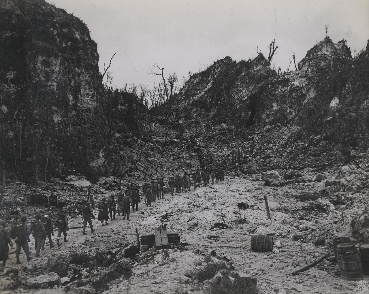 A column of Marines picking their way through jagged rocky ground
