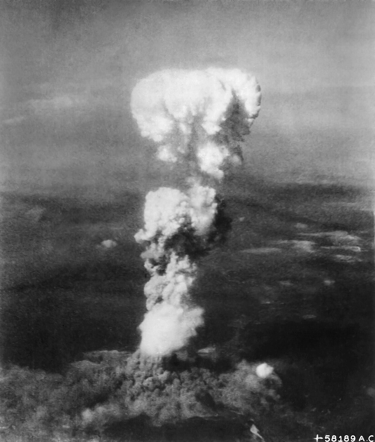 A vast column of smoke rising over a city, photographed from the air