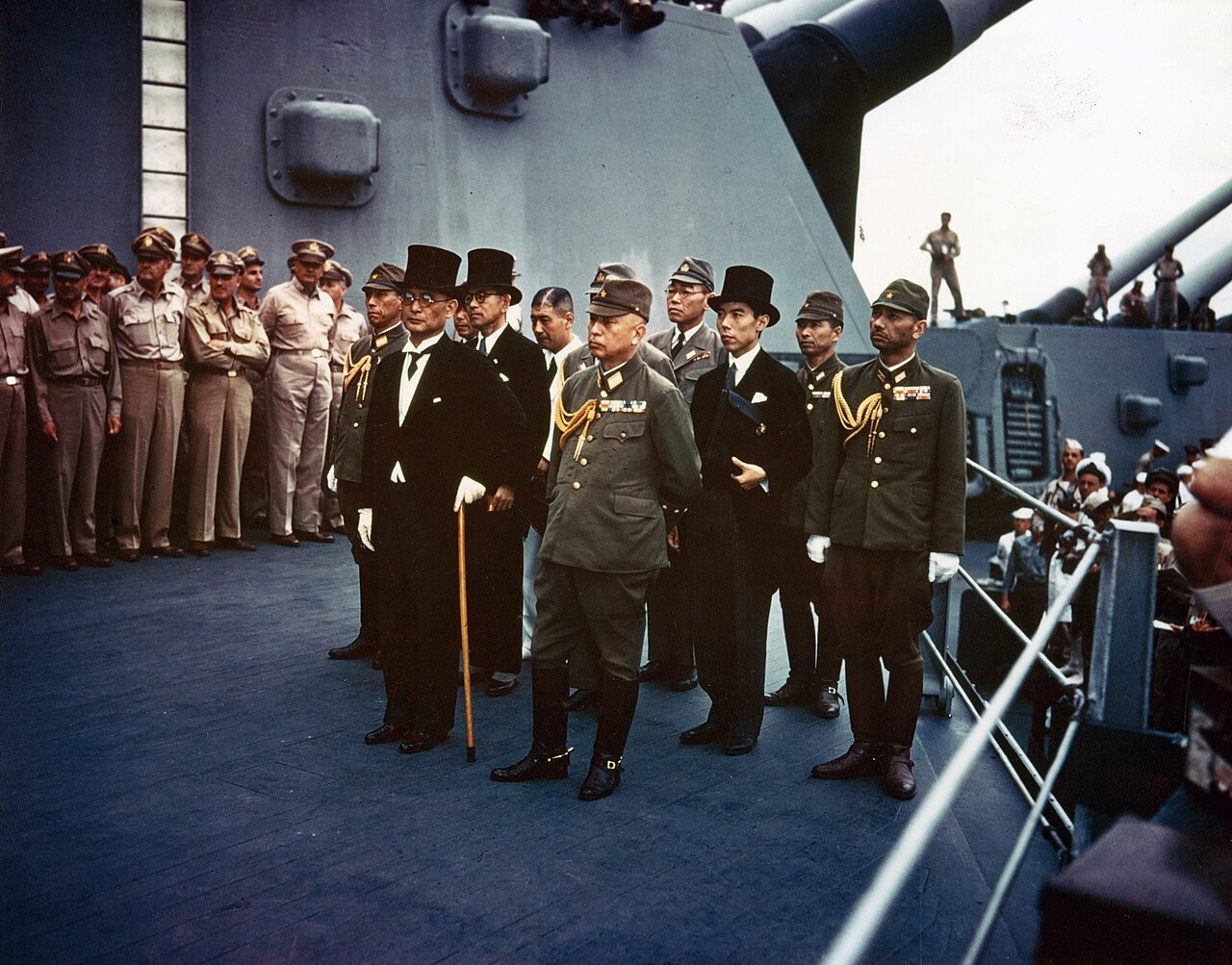 Japanese delegates standing in formation on a battleship deck facing Allied officers