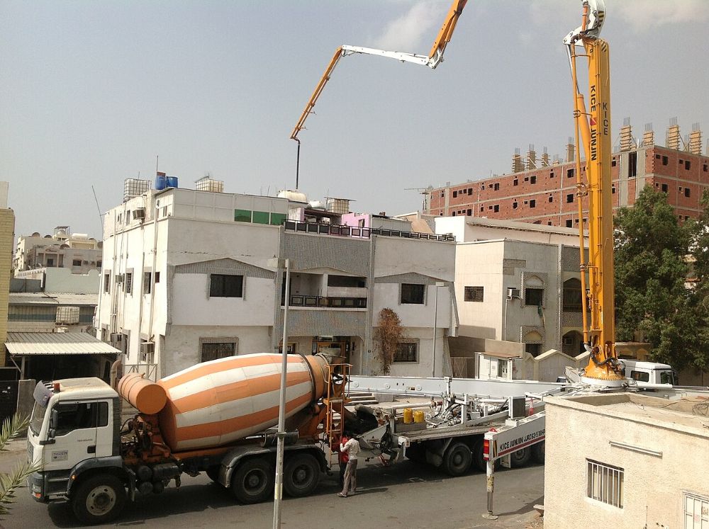 A concrete mixer truck feeding a boom pump at a building site