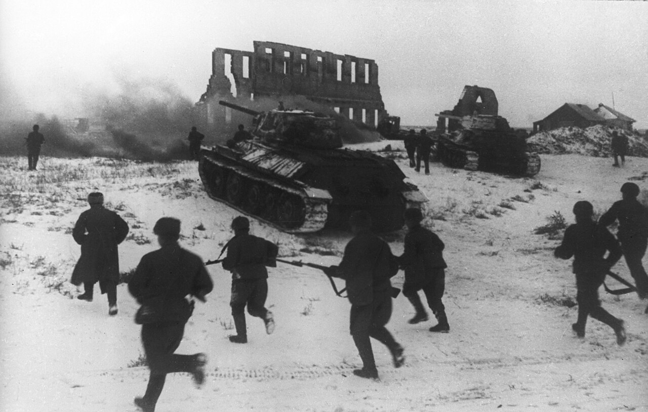 Soviet infantry running forward across snow past a burning vehicle