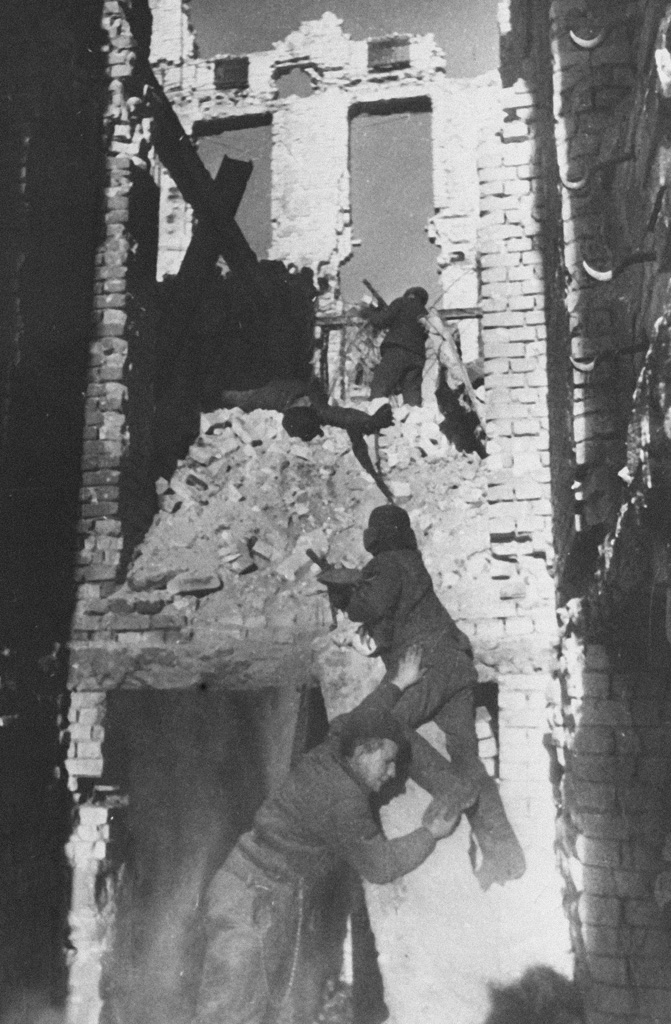 Soviet soldiers moving through the shell of a gutted multi-storey building