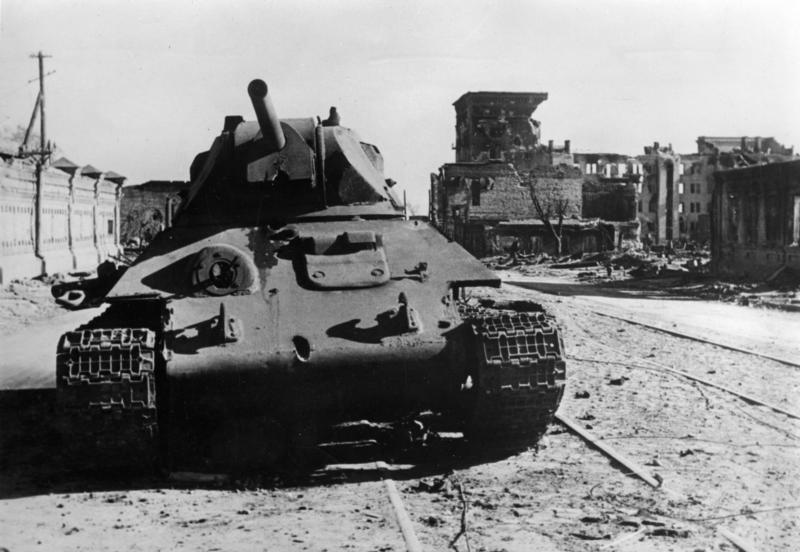 A knocked-out T-34 tank standing among rubble and wrecked buildings