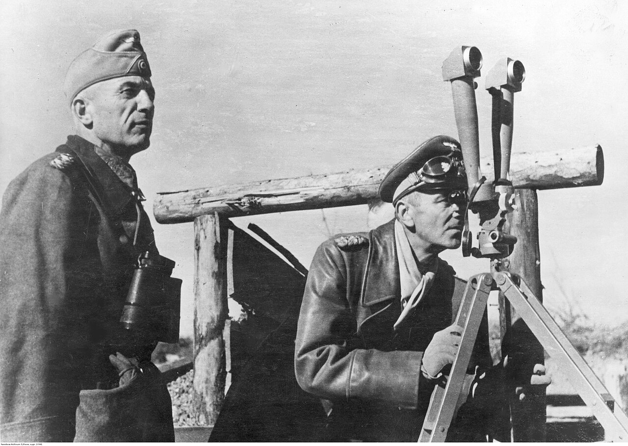 An officer looking through a tall scissor periscope mounted at a forward position